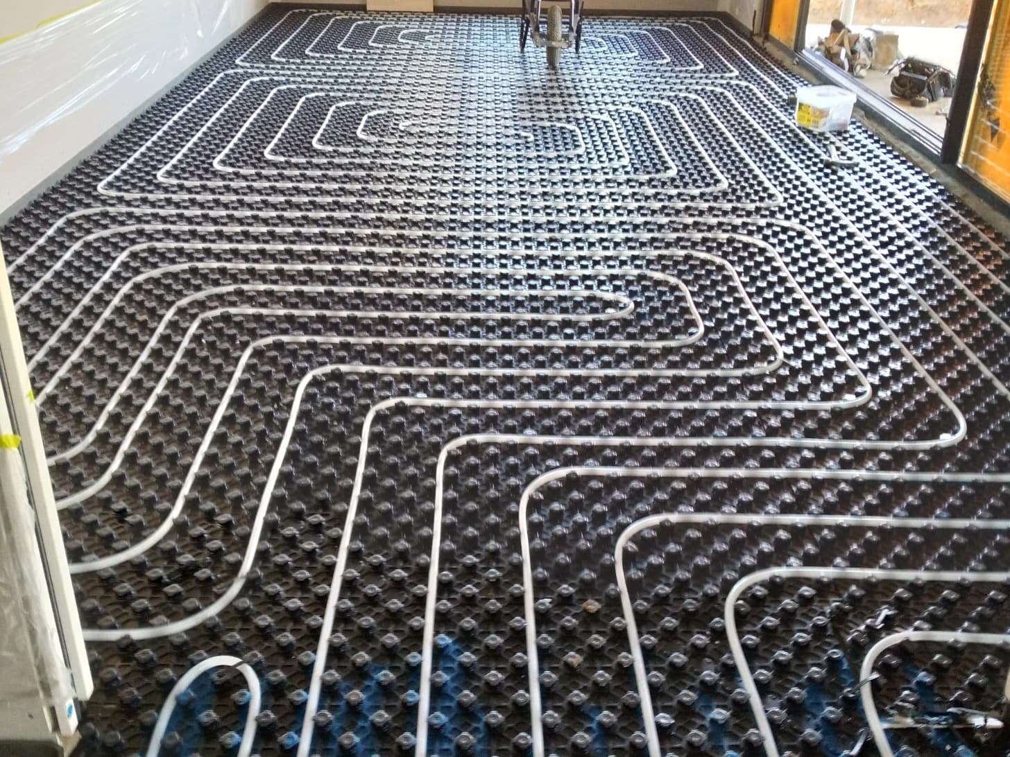 Straight in-screed hydronic heating pipe runs fixed across an interior floor area