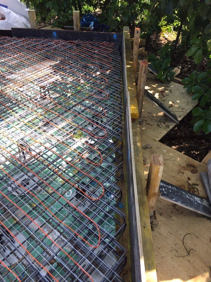 In-slab electric heating cables laid across reinforcement mesh before the concrete pour.