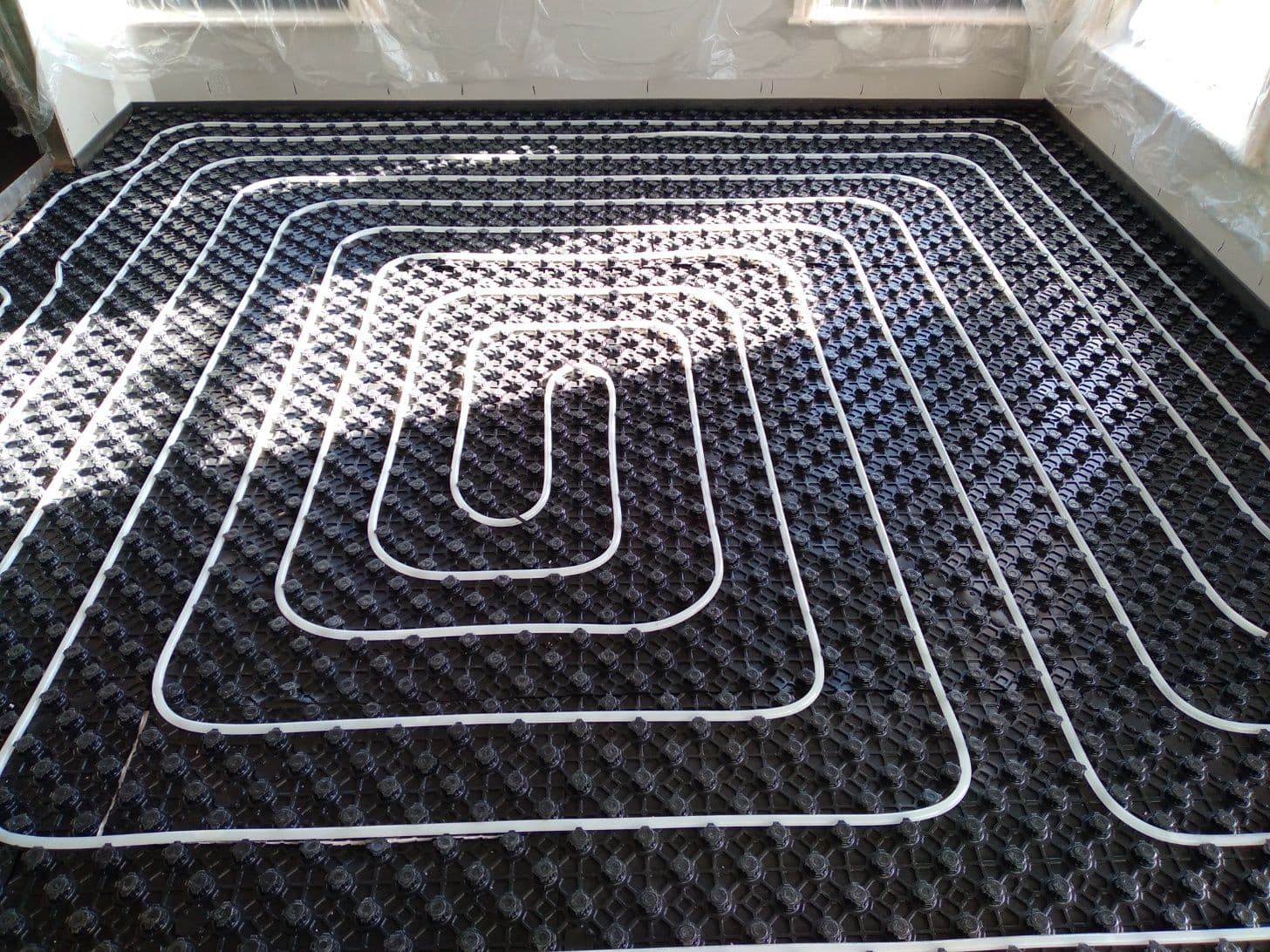 Hydronic heating pipes coordinated around a central floor opening on Profi Duo boards.