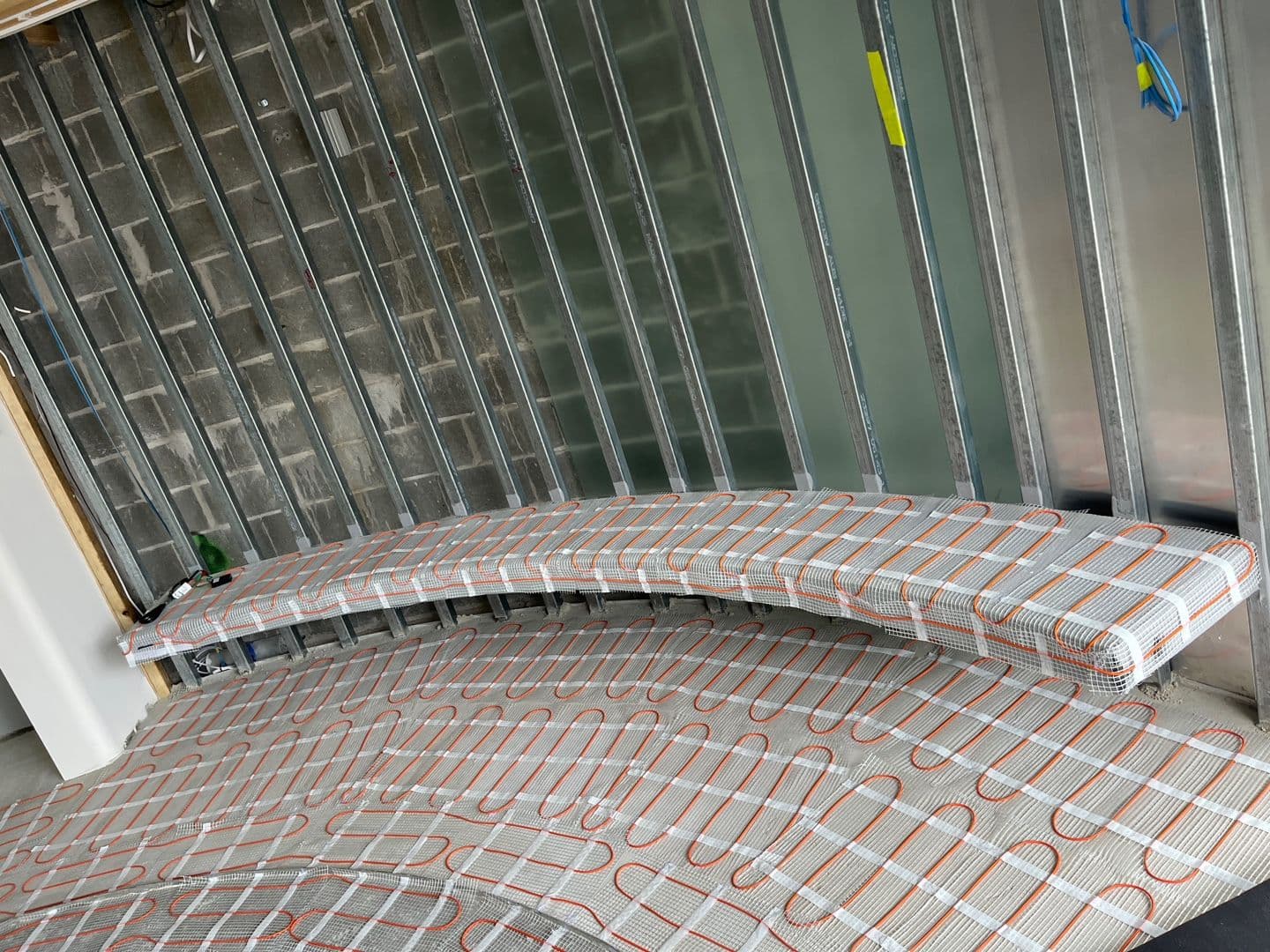 Electric heating mats installed across curved seating and floor areas in a Bellevue Hill wellness room.