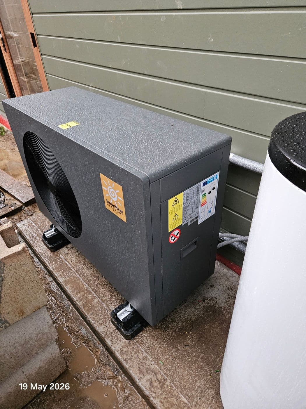 Residential heat pump and buffer tank arranged within a narrow side access area.