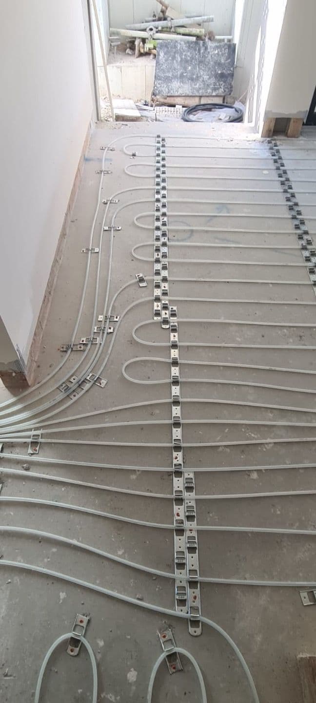 Multi-zone hydronic underfloor heating pipework installed across a large residential floor.