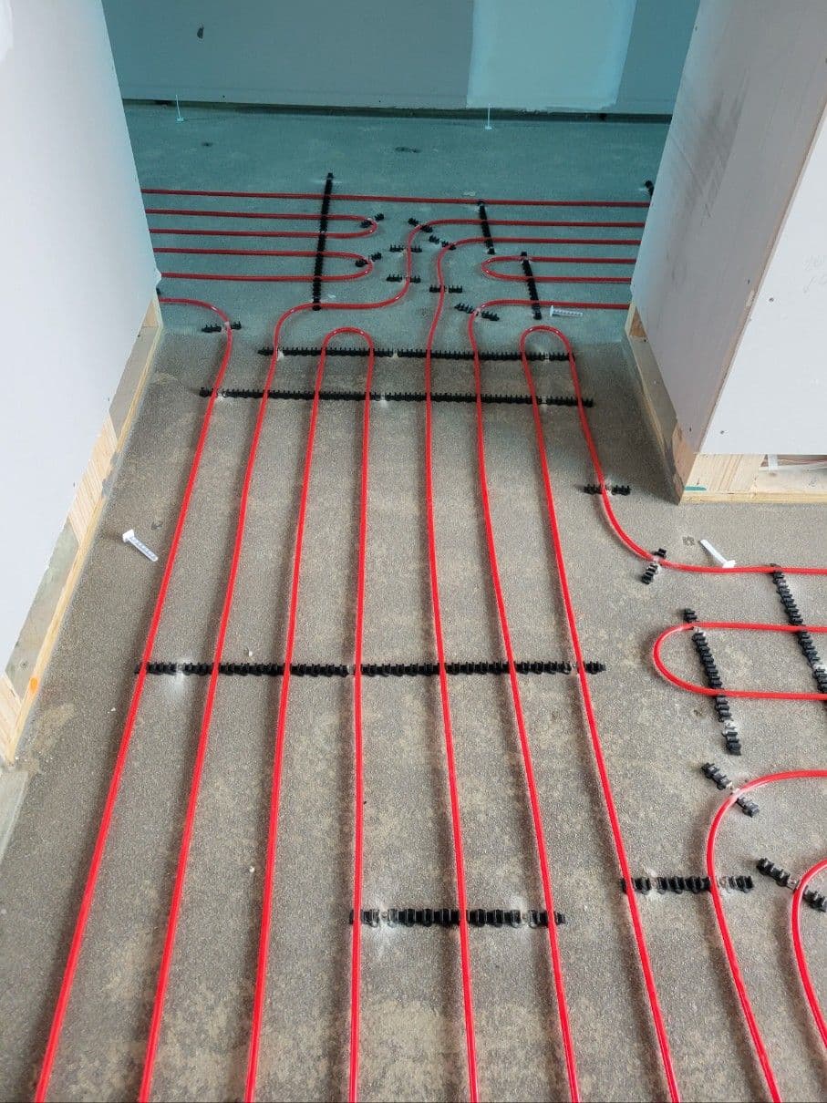 Hydronic underfloor heating pipes arranged around walls and residential service areas.