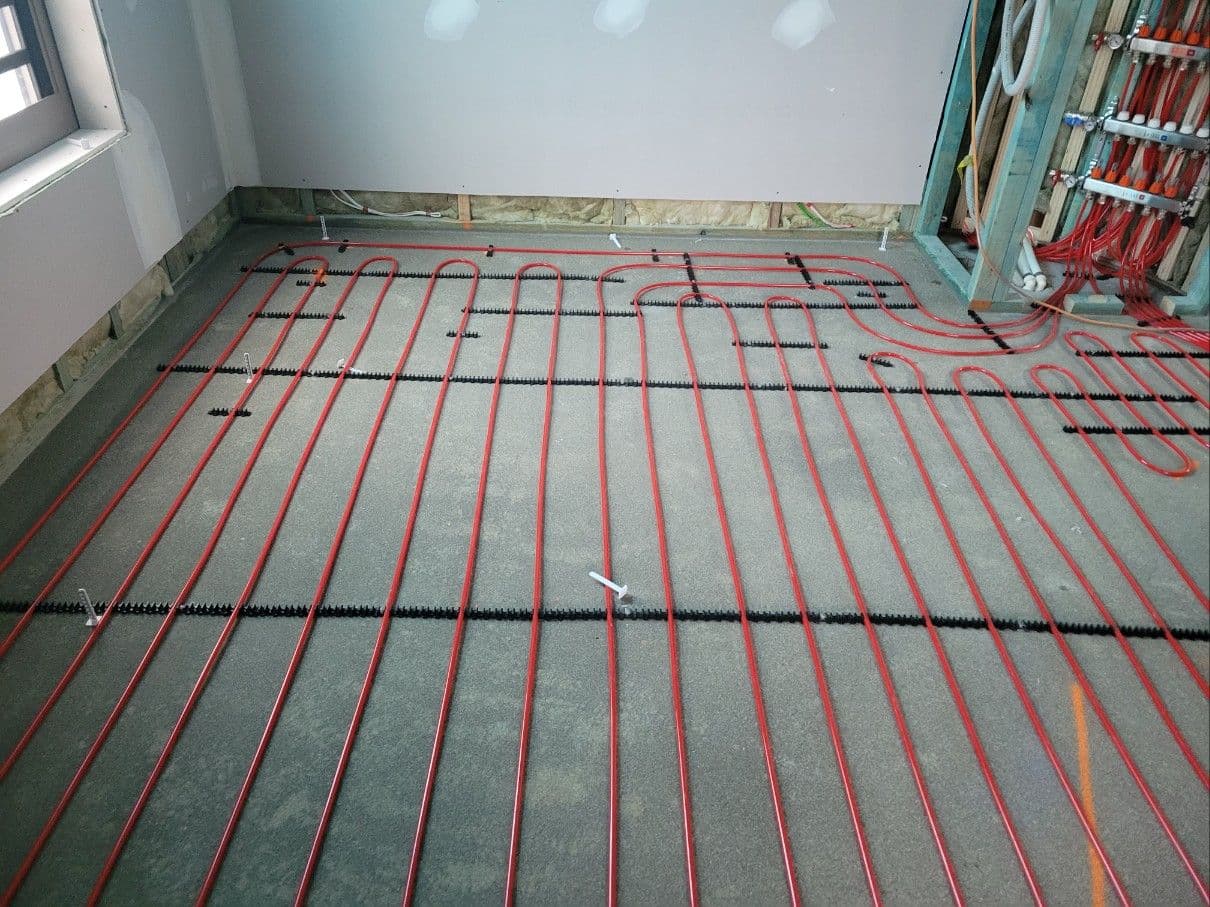 Hydronic heating pipes installed across a large residential room before screeding.