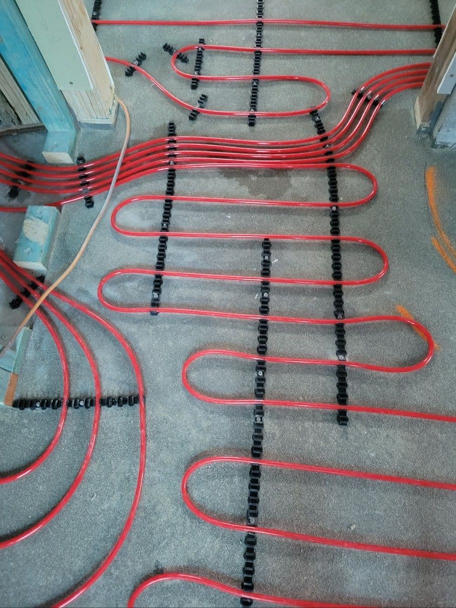 In-screed hydronic pipework routed from the manifold into multiple heating zones.
