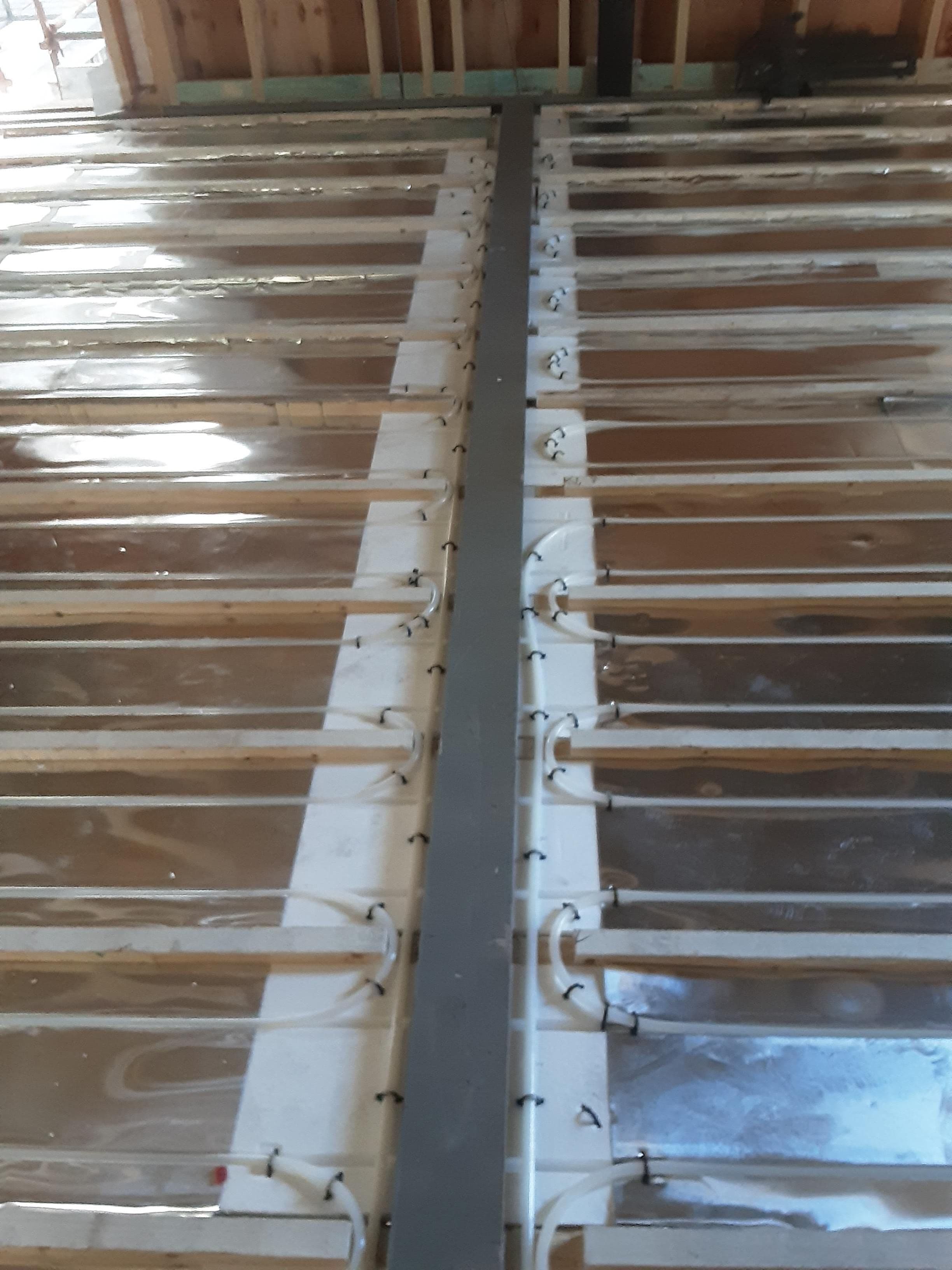 Hydronic underfloor heating pipe layout installed across a framed residential floor.